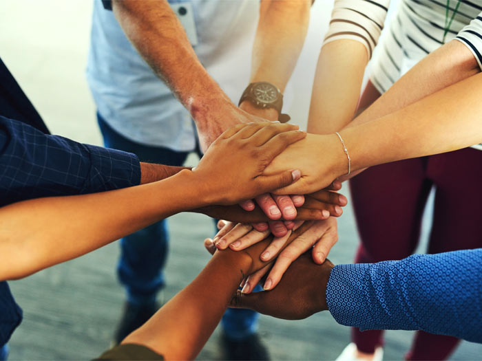 Cinq personnes en caucus mettent leurs mains les unes sur les autres en signe de soutien mutuel.