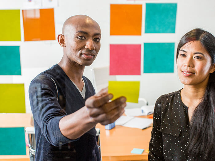 Colleagues reading adhesive notes in office