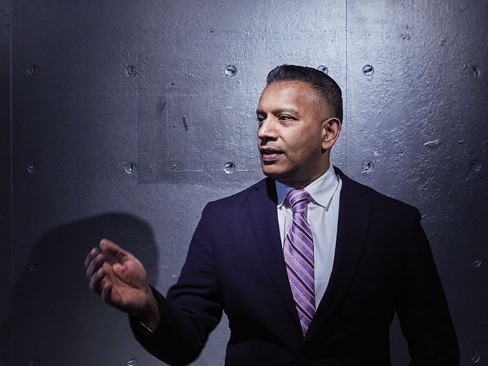 A businessman stands in front of a cement wall