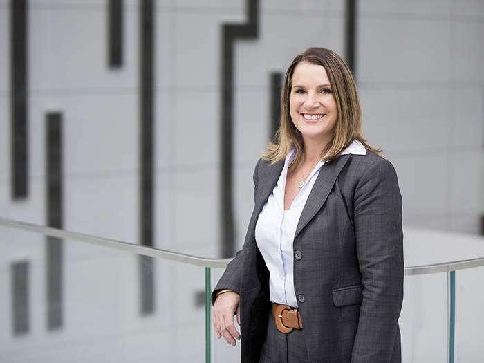 A businesswoman stands next to a railing