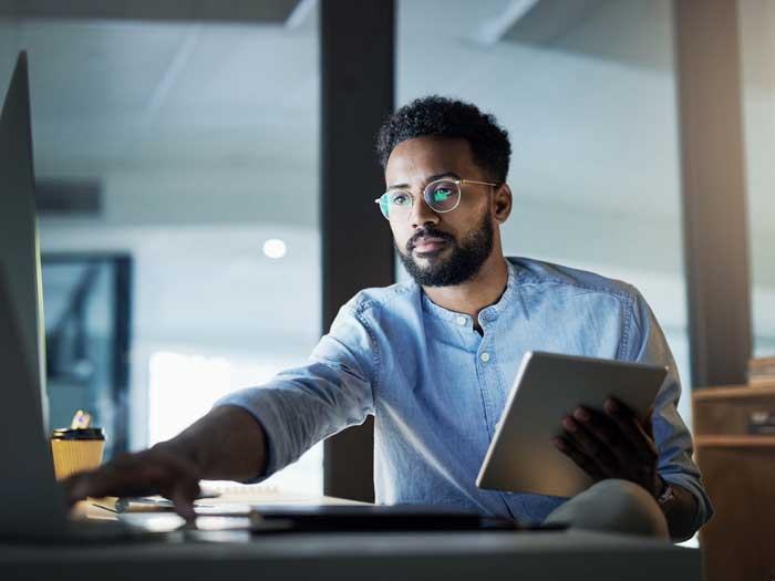 Shot of a young businessman using a digital tablet in an office at night