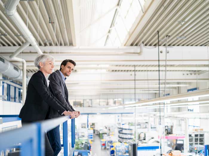 Two business people stand by a railing overlooking a warehouse