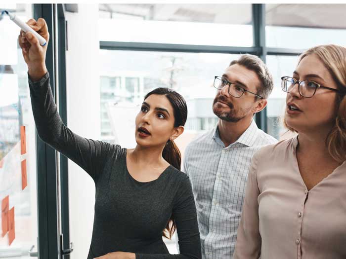 Plan d'un groupe d'hommes d'affaires faisant du brainstorming avec des notes sur un mur en verre dans un bureau